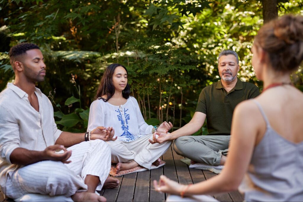 People practicing seated meditation during a yoga session in nature, Living Church Serving Richmond.