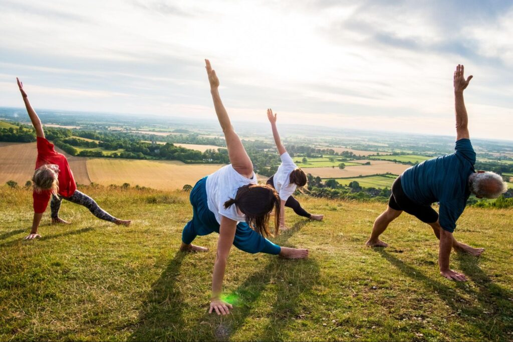 A group of people taking part in a spiritual practice outside on a grassy hill Living Church Serving San Mateo.