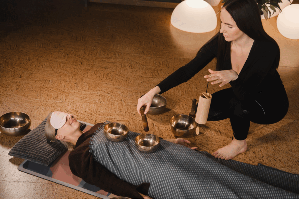 A woman performing a sound bath on a female client.