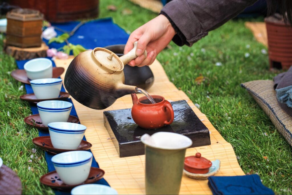 A person pouring tea from a teapot into a teacup during a traditional tea ceremony.