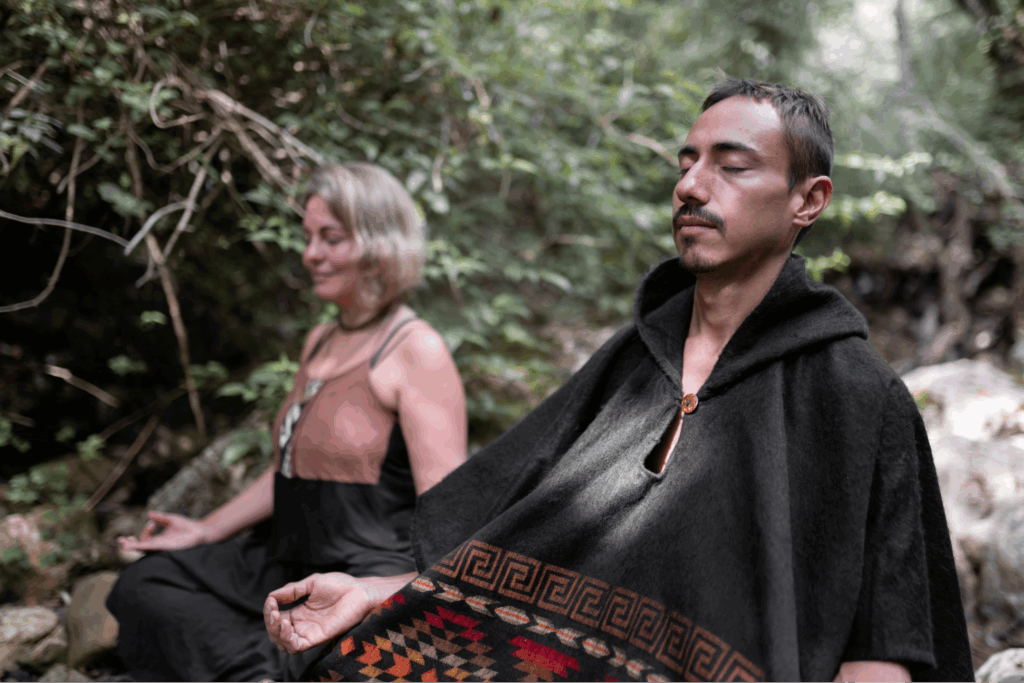 A man and a woman meditating in the woods.