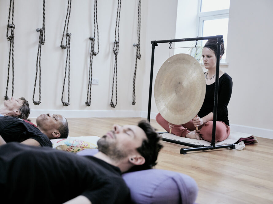 A woman prepares to use a gong to provide a sound bath to participants.