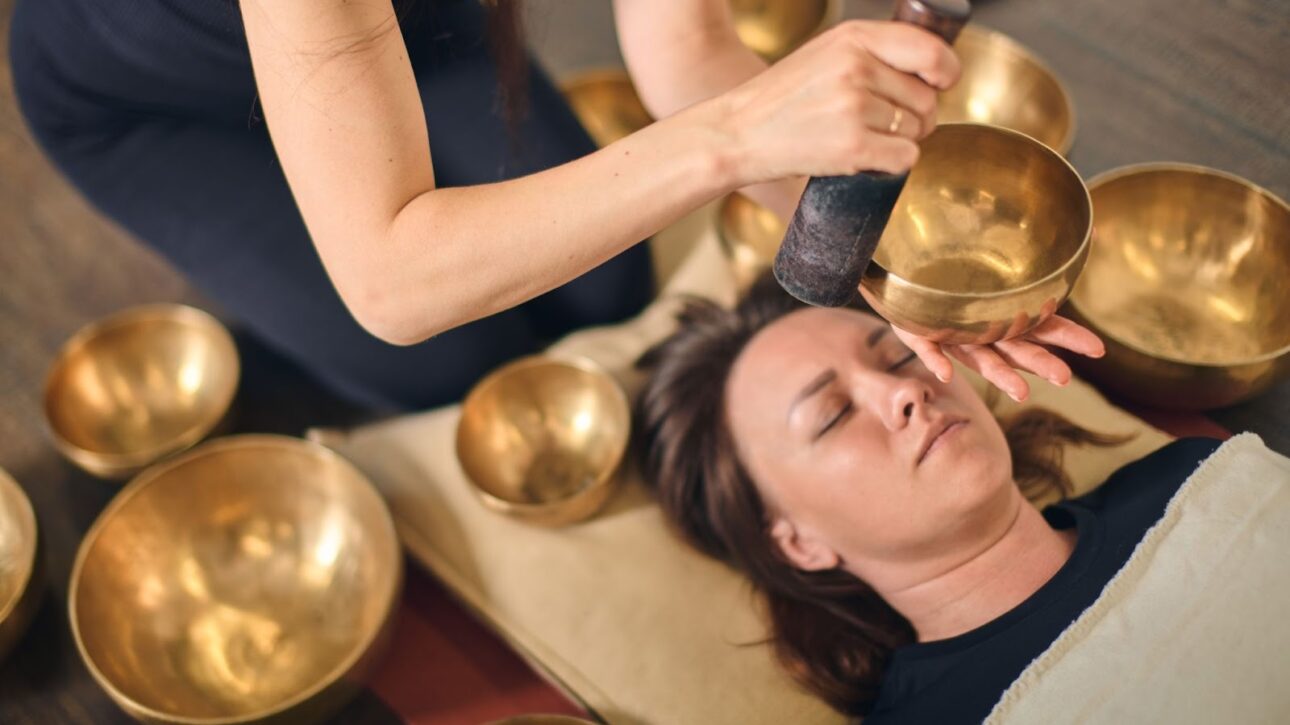 A woman in a serene sound bath led by a sound healer using Tibetan singing bowls