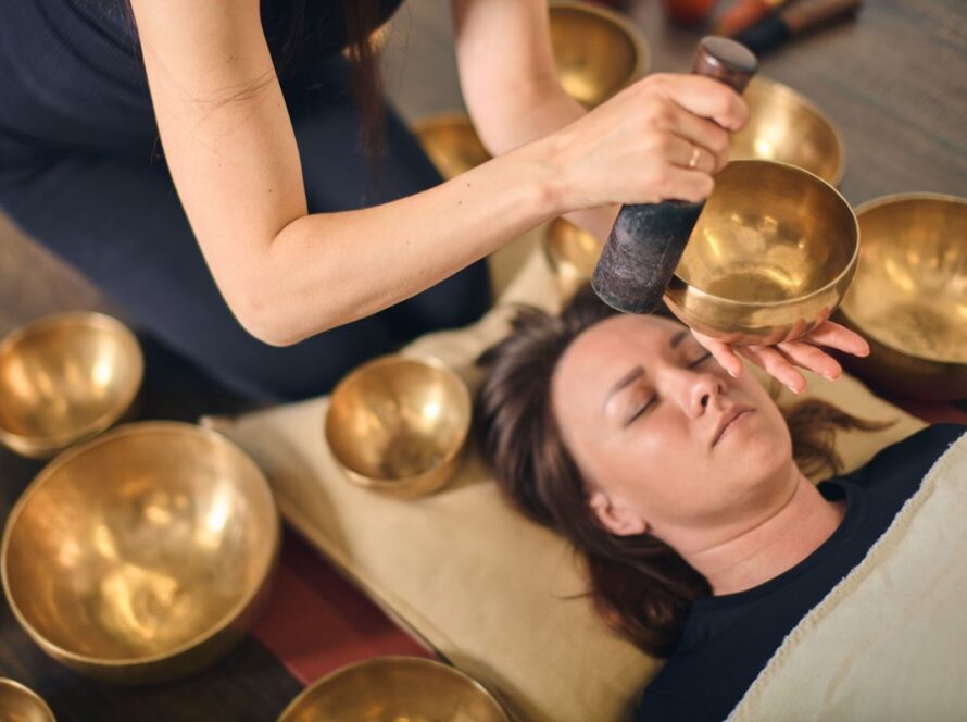 A woman in a serene sound bath led by a sound healer using Tibetan singing bowls
