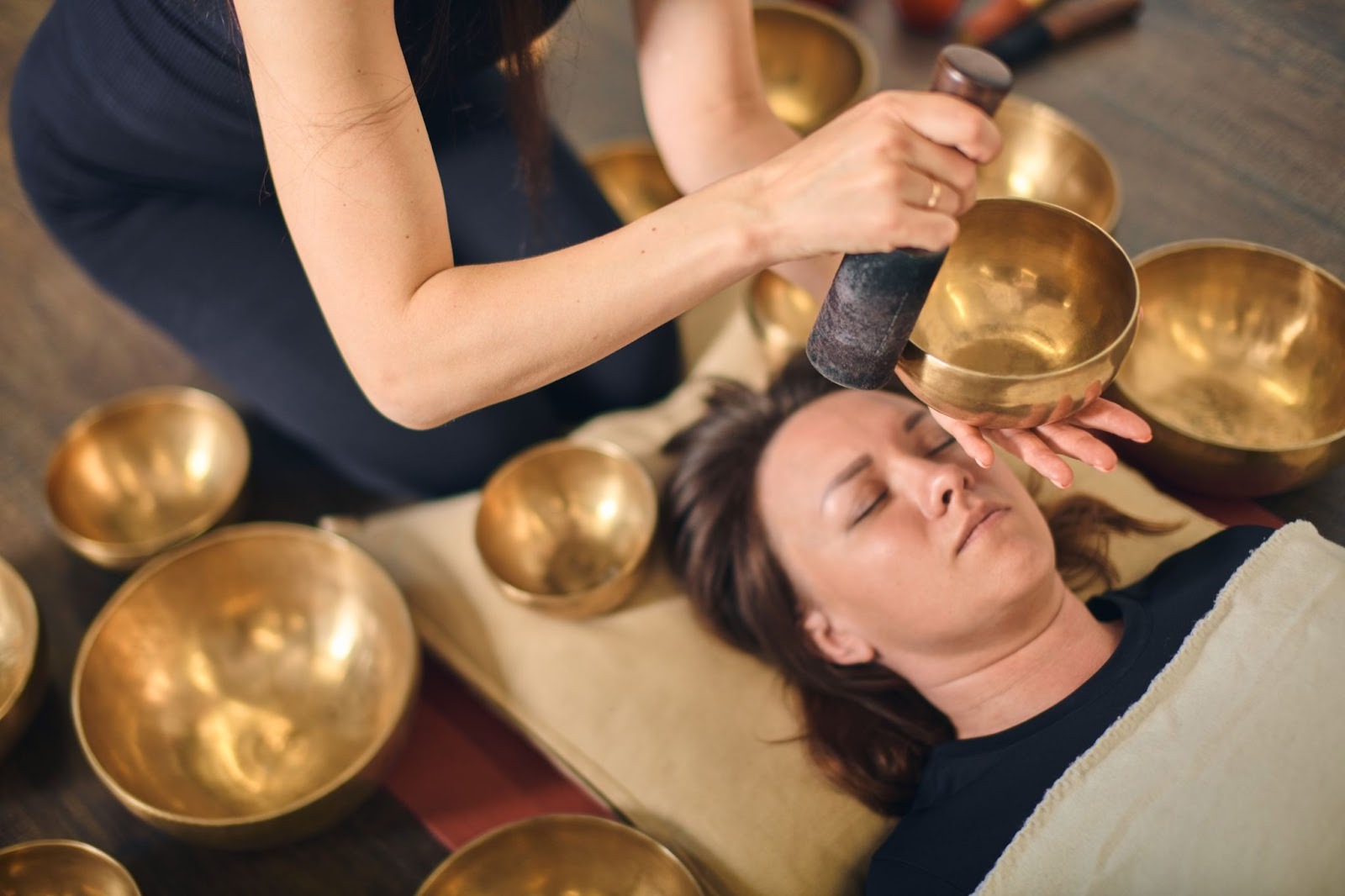 A woman in a serene sound bath led by a sound healer using Tibetan singing bowls