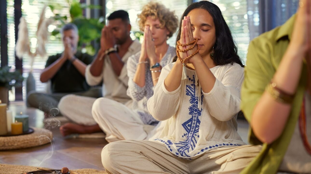 Group of people meditating with malas and hands gently clasped