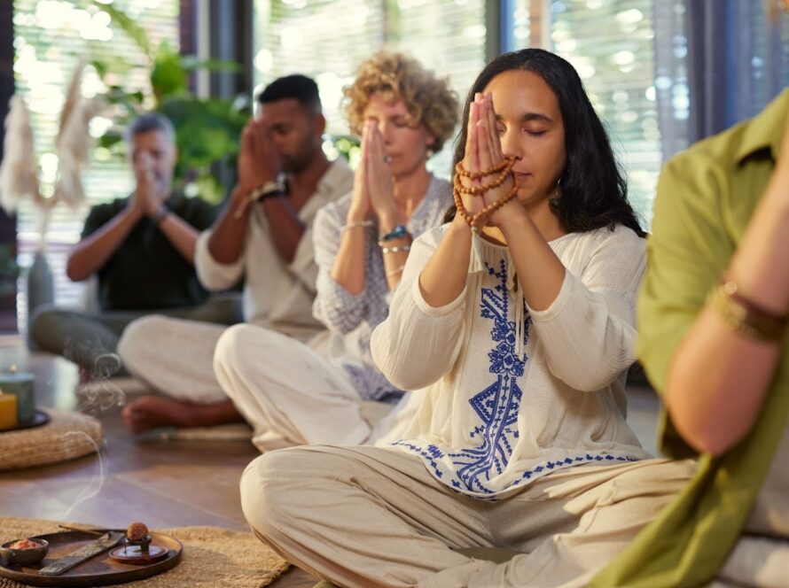 Group of people meditating with malas and hands gently clasped
