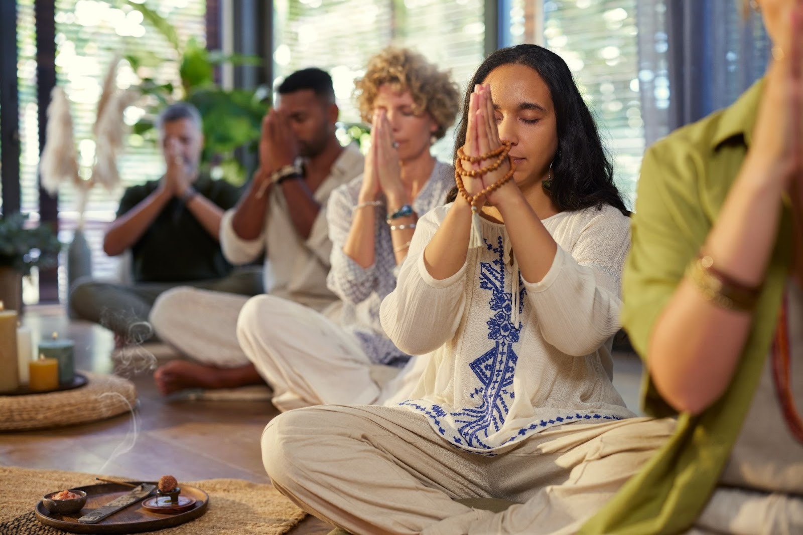 Group of people meditating with malas and hands gently clasped