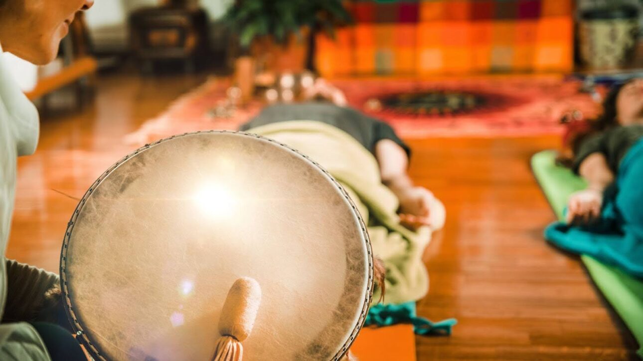 Two people lying down during a sound bath given by an instructor.