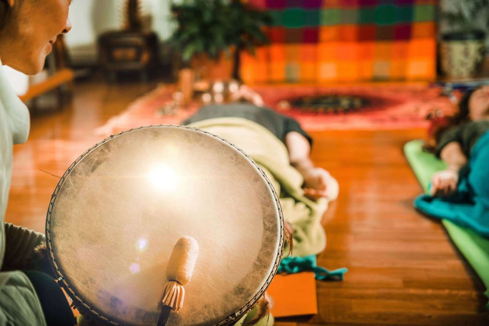 Two people lying down during a sound bath given by an instructor.