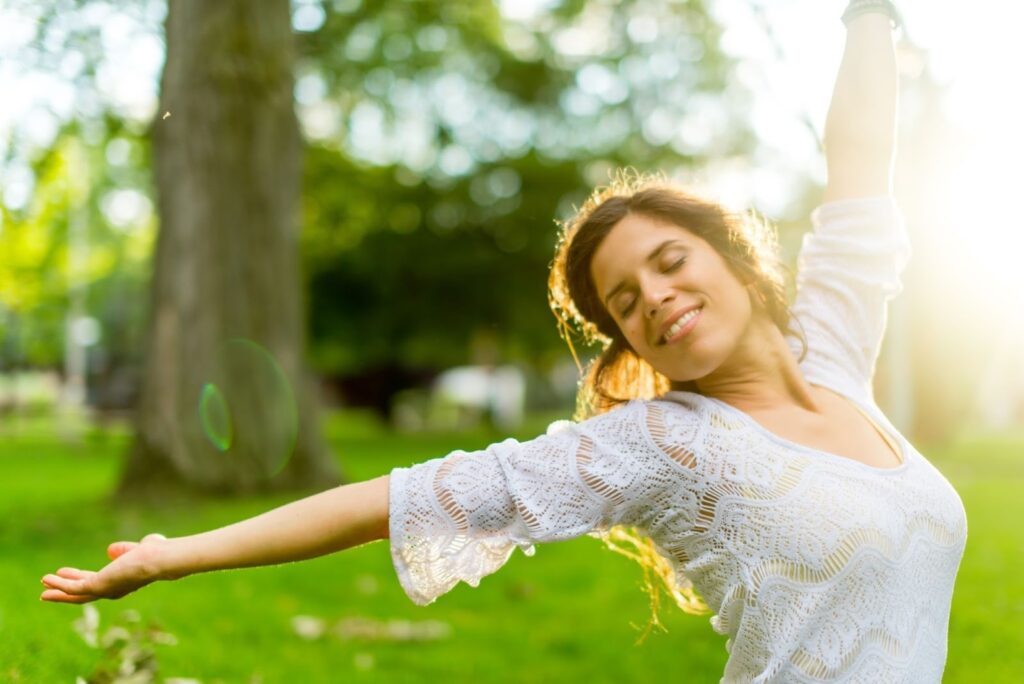 A multi-ethnic girl experiencing calm and warmth following meditation stretches her arms in delight.