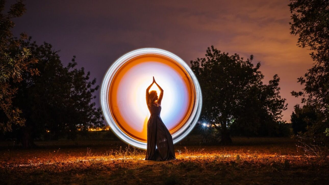 ​​Glowing circular light around a female silhouette in nature, representing spiritual energy, balance, and mindful presence.