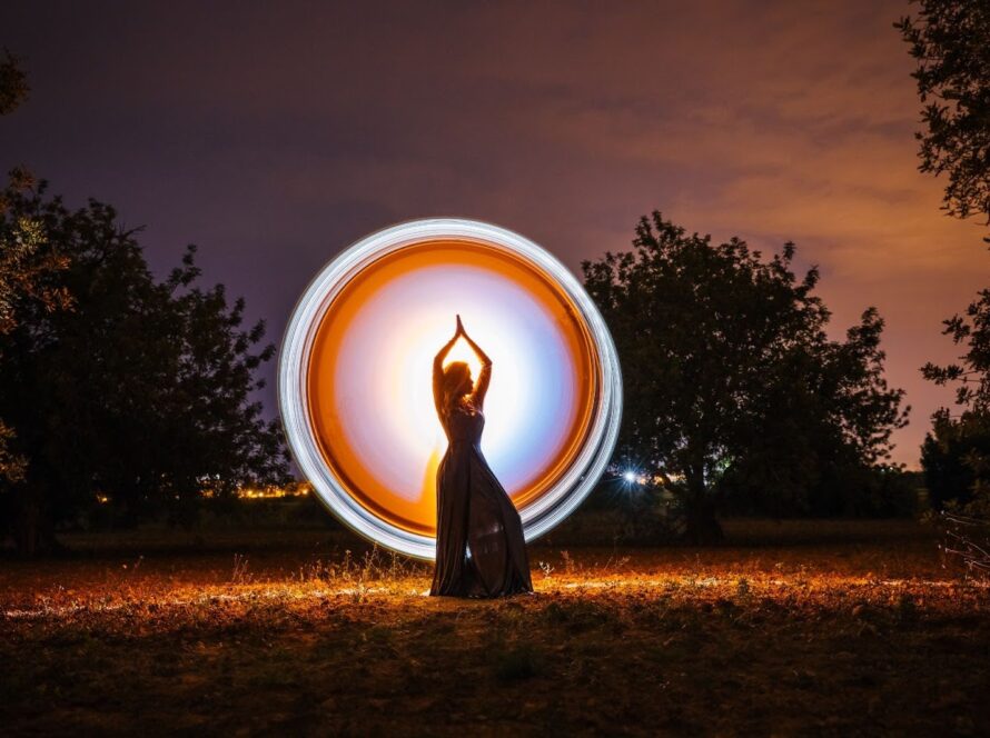 ​​Glowing circular light around a female silhouette in nature, representing spiritual energy, balance, and mindful presence.