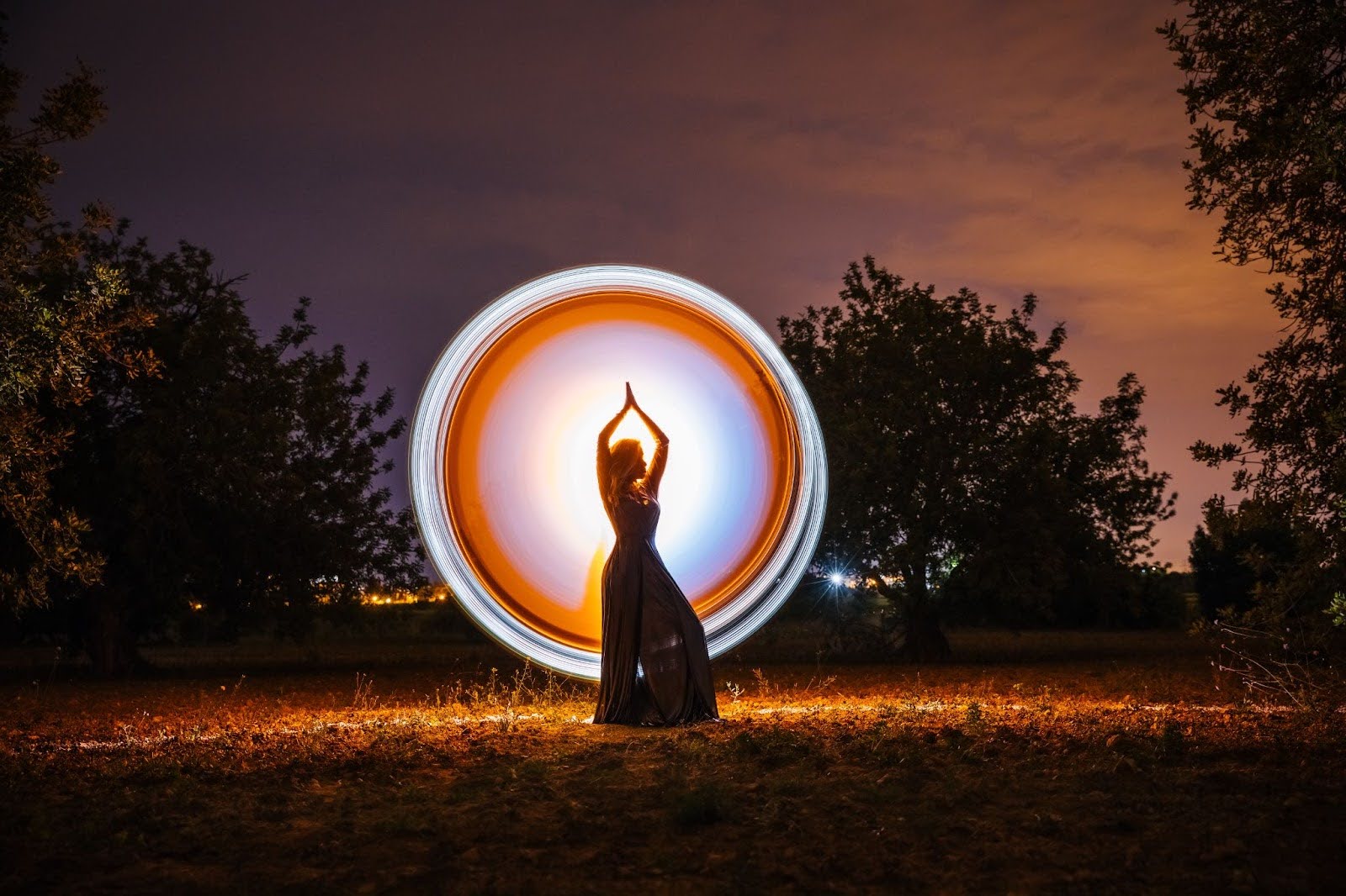 ​​Glowing circular light around a female silhouette in nature, representing spiritual energy, balance, and mindful presence.