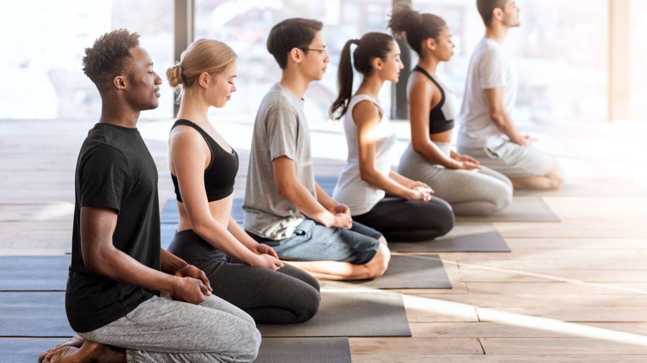 Diverse young adults participating in a beginner meditation exercise focused on breathing and relaxation.