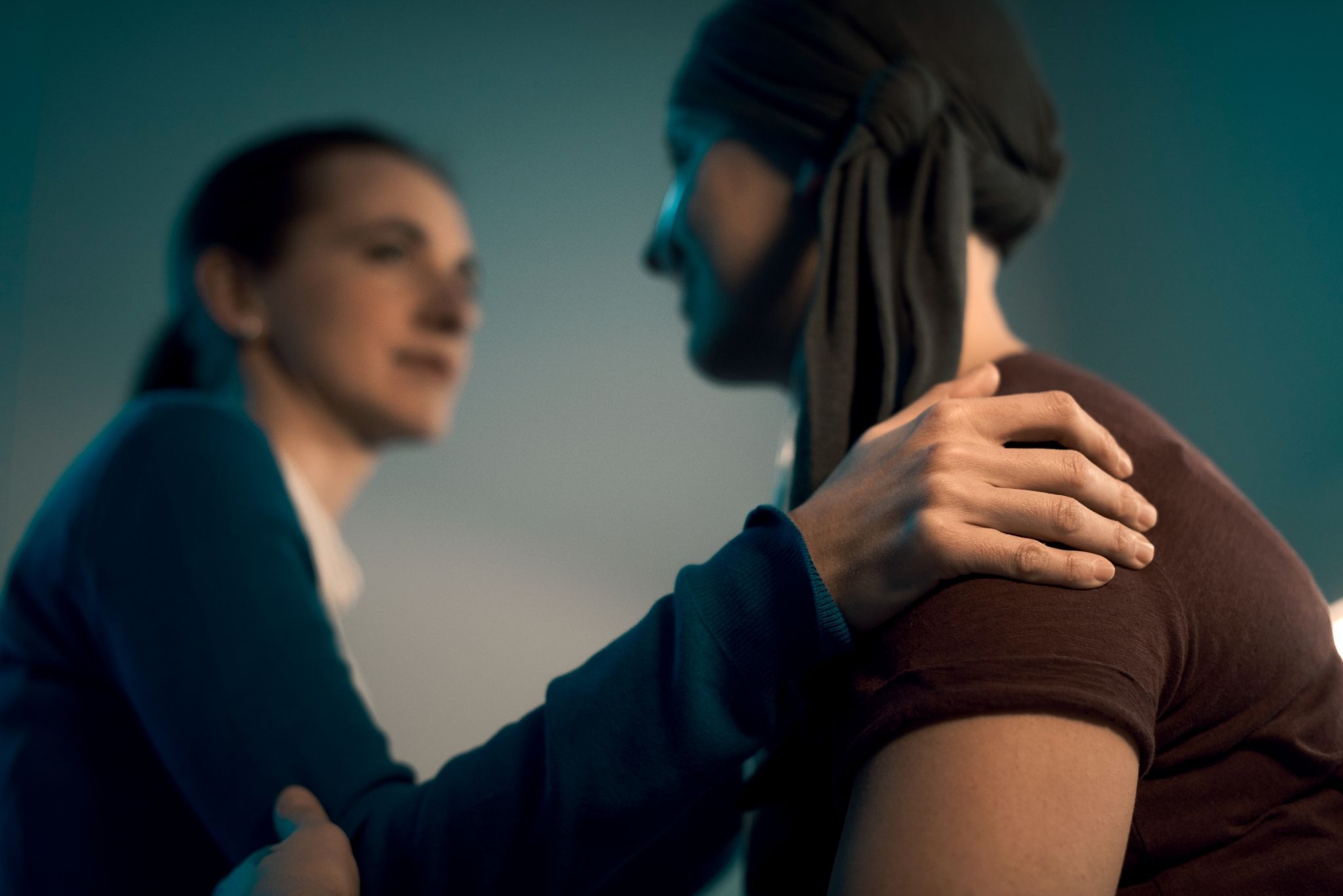 A female friend providing comfort to a woman in a headscarf during an emotional moment