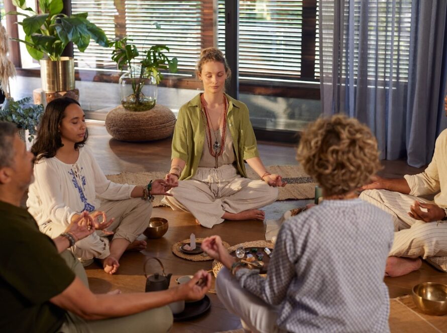 Multiethnic group practicing guided meditation in a circle, seated calmly with eyes closed and focused on mindful breathing together.