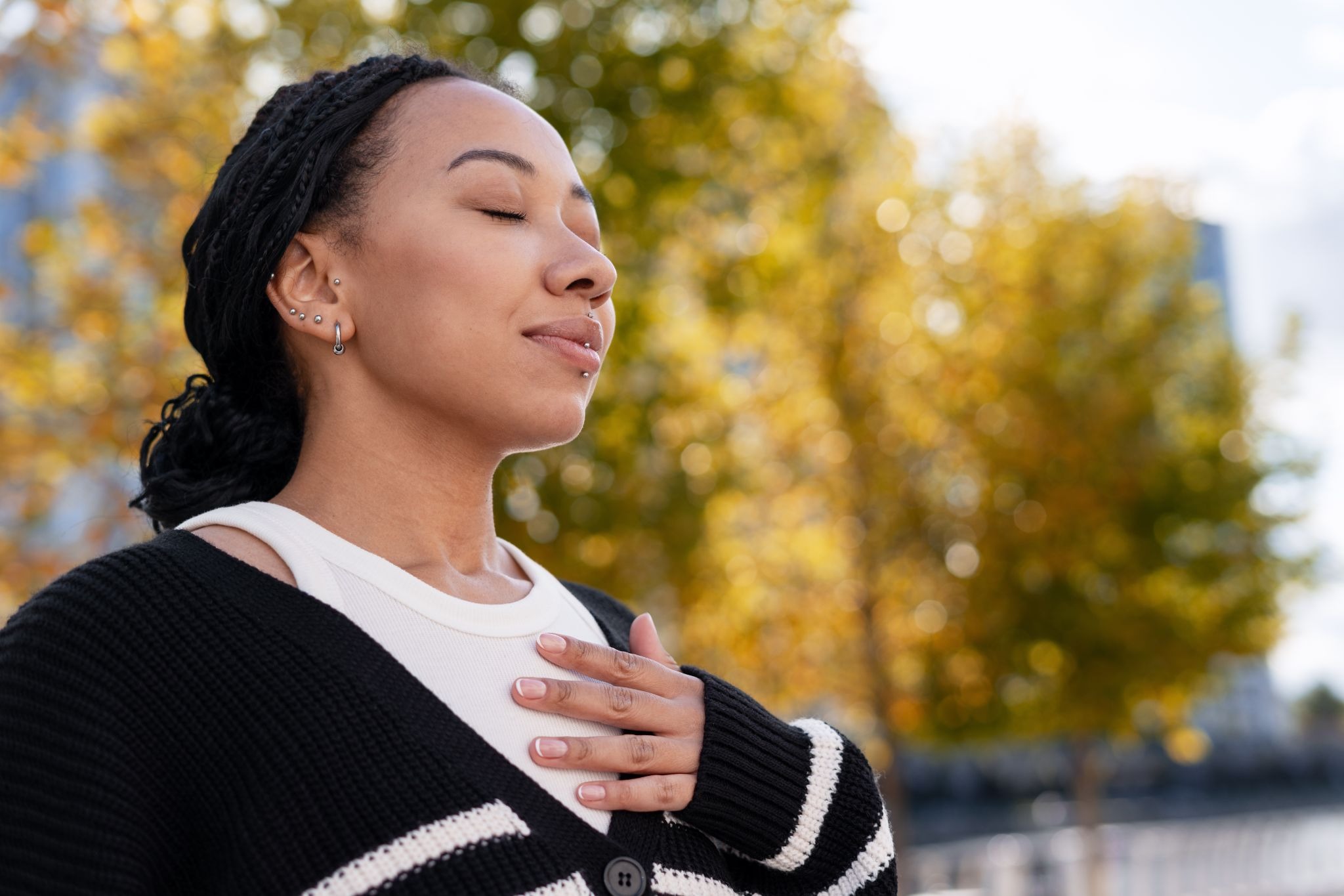 Woman practicing mindful breathing on a city street, using simple breathwork techniques to stay calm and focused amid urban surroundings