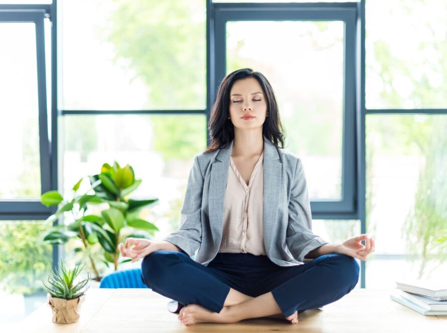 Businesswoman meditating to relieve stress at her office desk with eyes closed