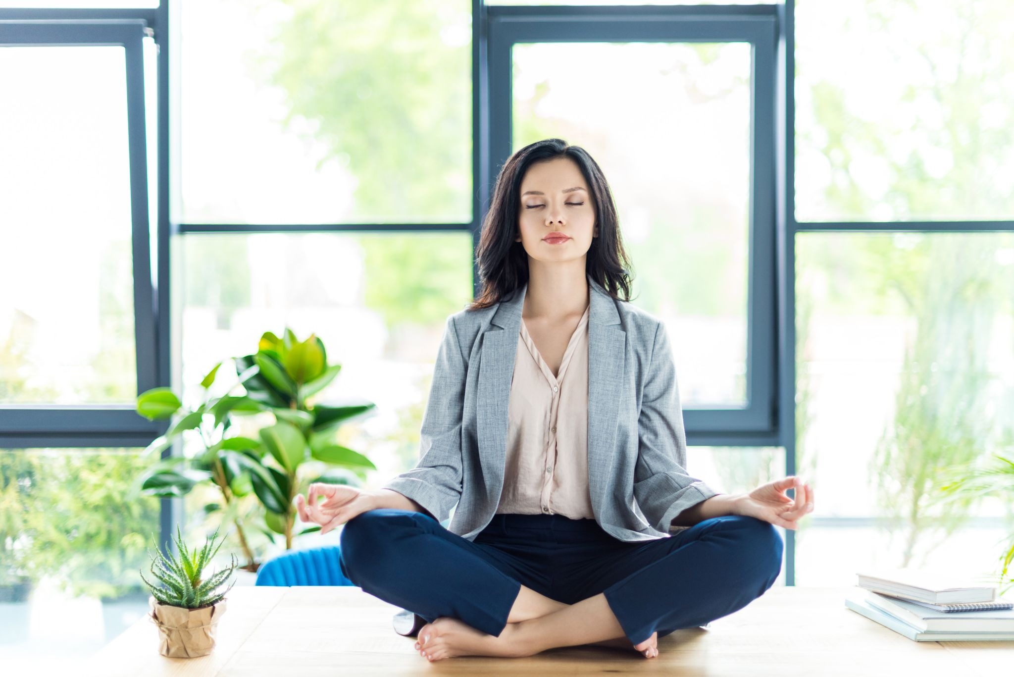 Businesswoman meditating to relieve stress at her office desk with eyes closed